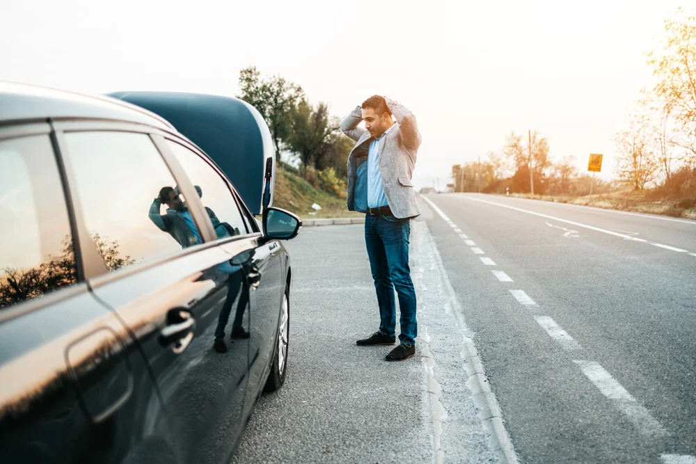 Man on side of the road with car broken down